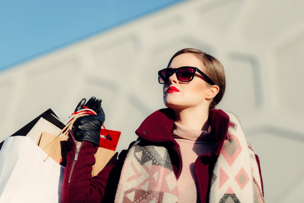Bilde viser en dame med solbriller som holder flere handleposer.