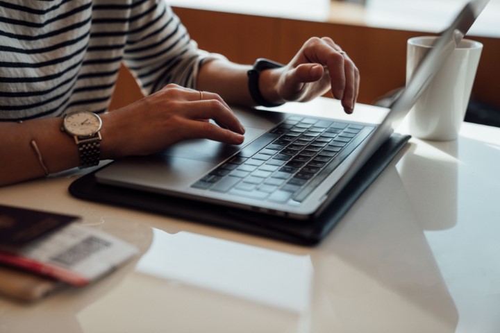 Bildet viser et par hender som skriver på tastaturet på en laptop.