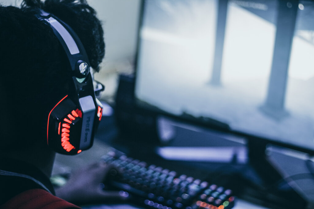 Bildet viser en person med lysende headset foran en PC.